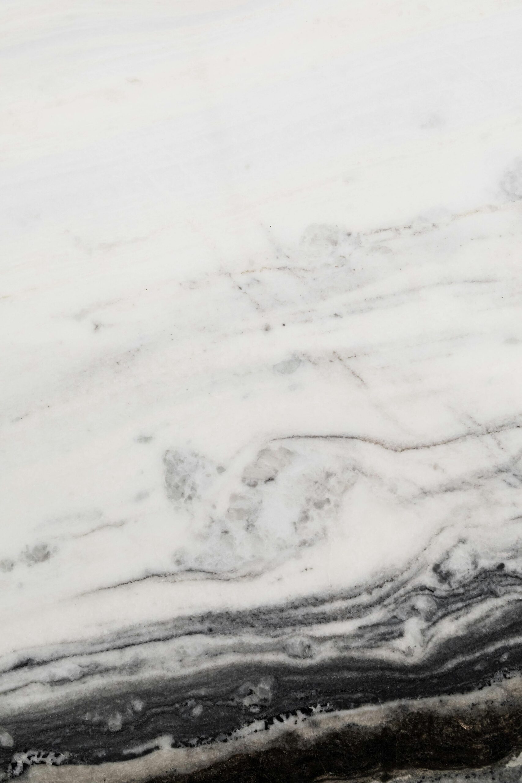 Close-up view of a white marble surface adorned with natural dark veins and patterns.